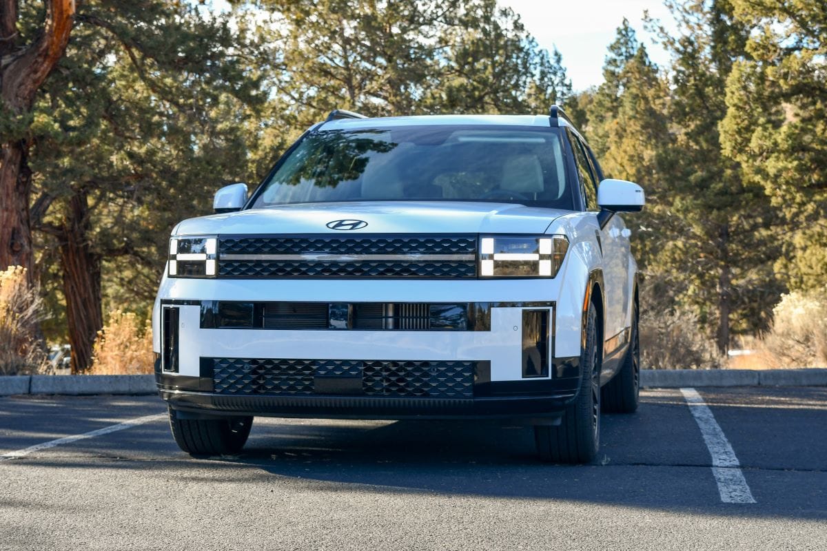 Are Hybrid Cars Worth Paying Extra? Here's What You Need to Know, and How to Tell 9 Thew Front End Of The 2024 Hyundai Santa Fe In A Woodsy Parking Lot