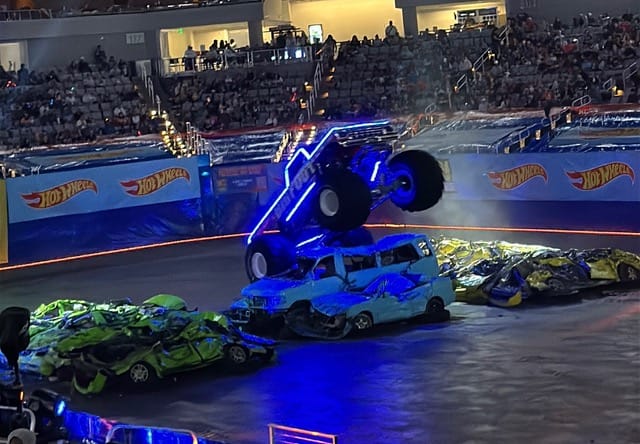 Hot Wheels Monster Trucks Live Glow Party Was the Boy-Mom Delight I Didn't Know I Needed 2 A Monster Truck With Neon Lighting Jumping Over Cars In Front Of The Audience At The Hot Wheels Monster Trucks Live Glow Party In Fort Worth, Texas