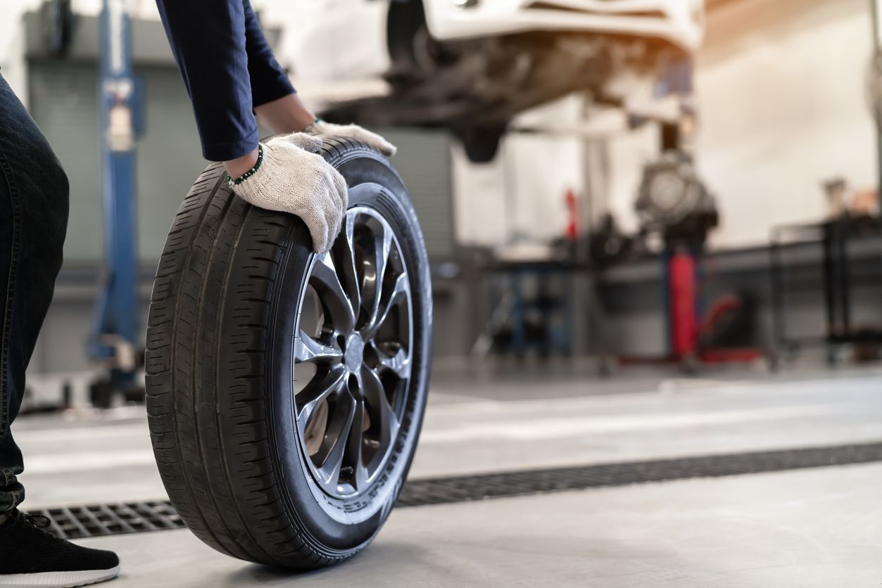 An automotive technician removes a tire from a car that's wearing unevenly due to a poor alignment