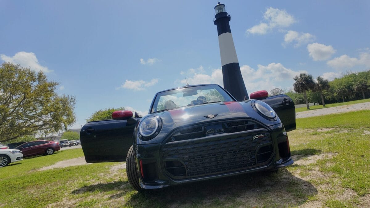 The New Mini Cooper Convertible Parked In Front Of A Scenic Lighthouse
