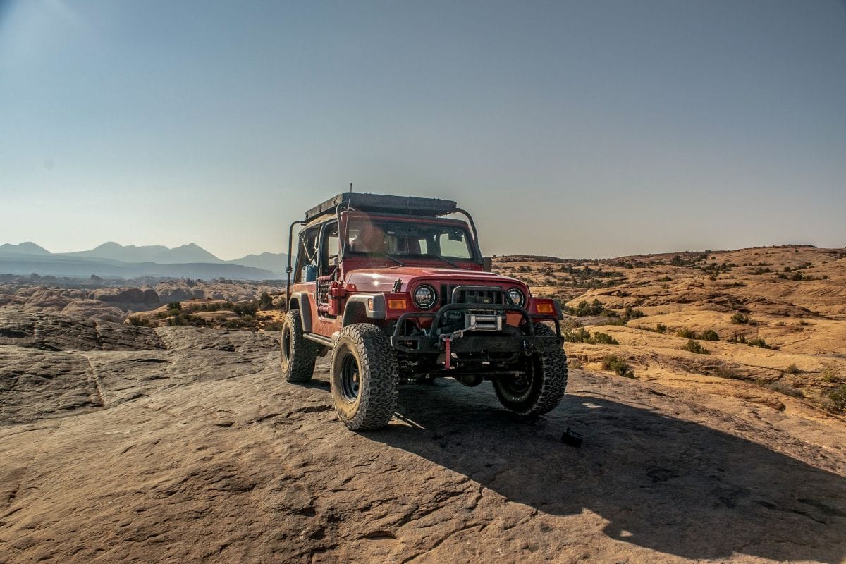 A flame red 2006 Jeep Wrangler Unlimited on Moab's Hell's Revenge trail