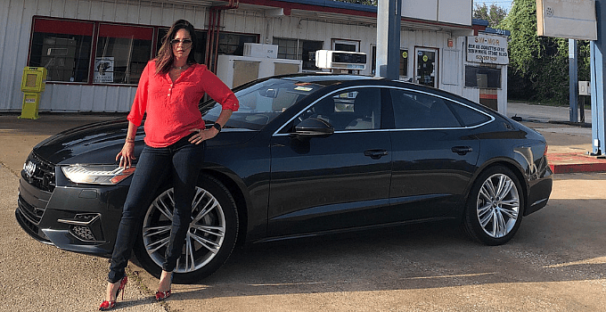 woman in read shirt standing next to Audi sedan