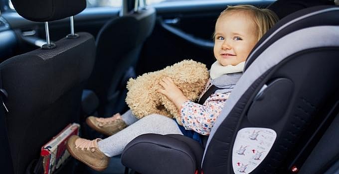 baby in car seat holding a teddy bear