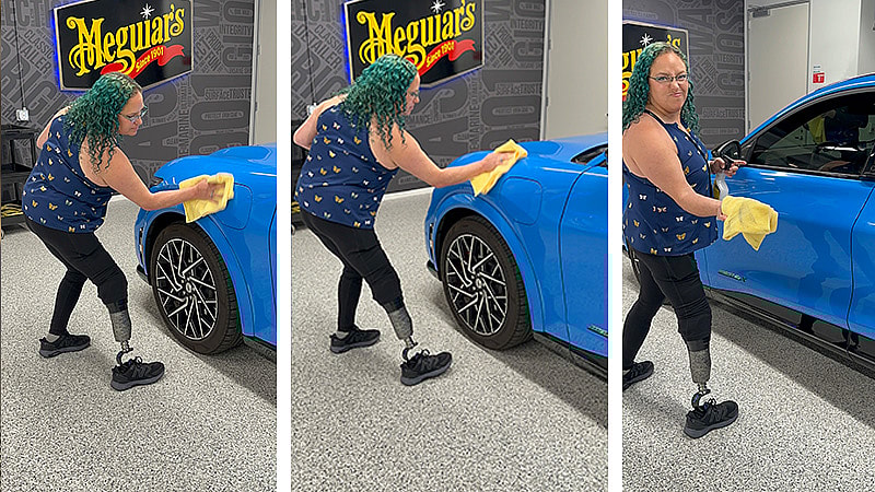 Green haired woman wipes a car with a yellow cloth.