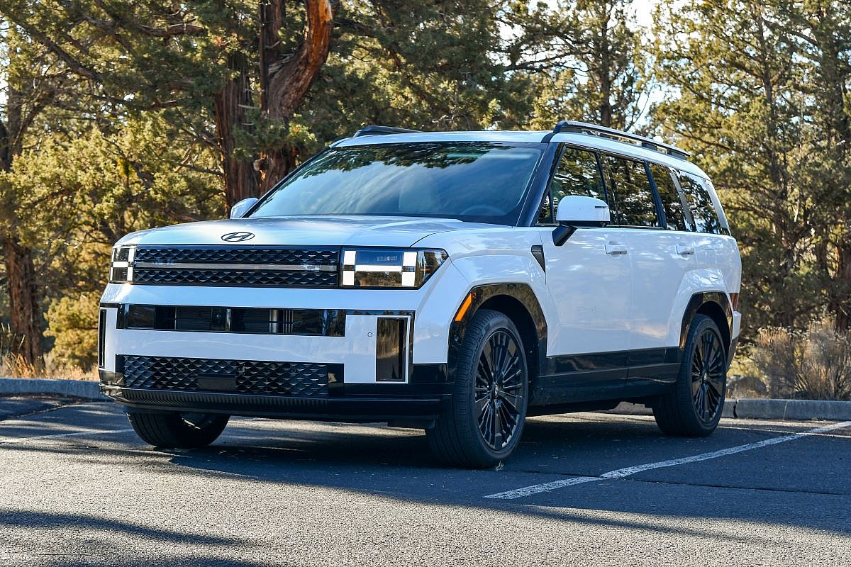 The 2024 Hyundai Santa Fe Hybrid parked in a shady spot with green trees in the background