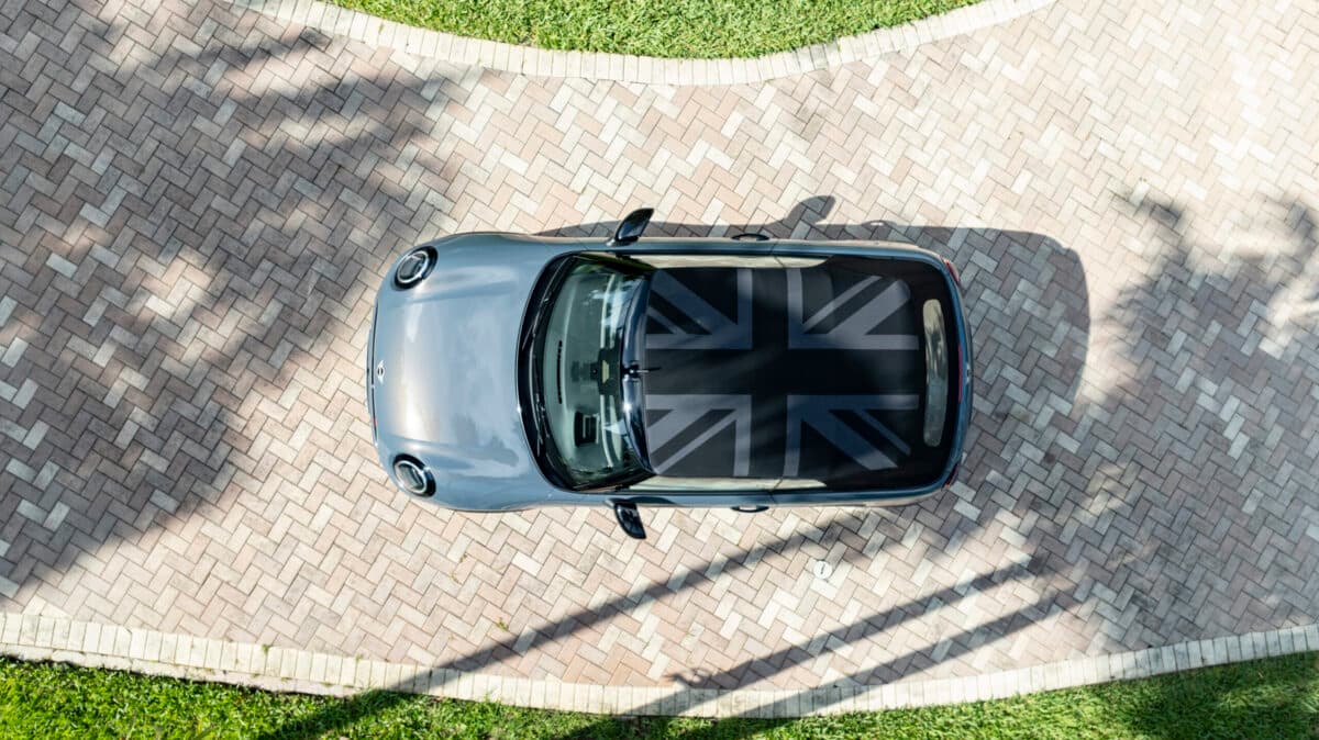 A 2025 Mini Cooper With The Optional Convertible Top Folded, Displaying The Union Jack Flag, Sitting In A Driveway