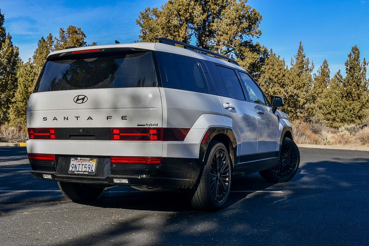 The Rear End Of The 2024 Hyundai Santa Fe Calligraphy Hybrid Parked In A Woodsy Parking Lot