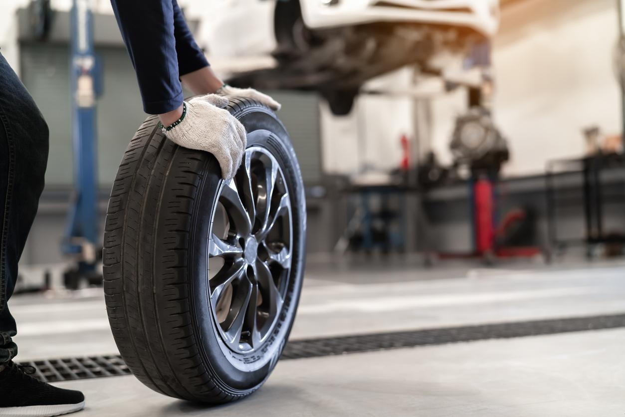 An Automotive Technician Removes A Tire From A Car That