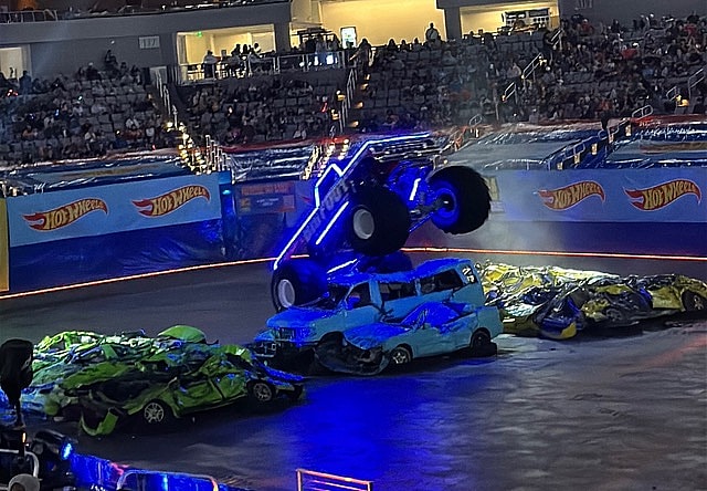A Monster Truck With Neon Lighting Jumping Over Cars In Front Of The Audience At The Hot Wheels Monster Trucks Live Glow Party In Fort Worth, Texas