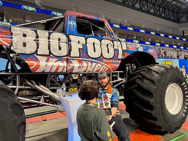 Hot Wheels Monster Trucks Live Glow Party Was the Boy-Mom Delight I Didn't Know I Needed 4 The Bigfoot Monster Truck, Its Driver, And A Young Boy Excited To Meet The Driver And Collect His Autograph
