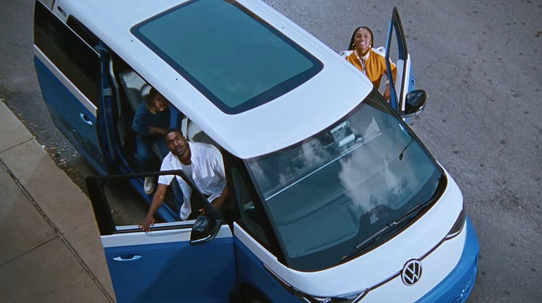 A Group Of Young People Waving Their Friend To Join Them In A Vw Id.buzz