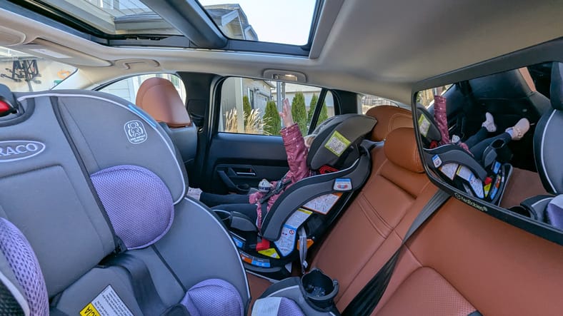 Car Seats Installed In The 2025 Mazda Cx-50 2.5 Turbo Premium Plus, With A Toddler Reaching Toward The Large Sunroof