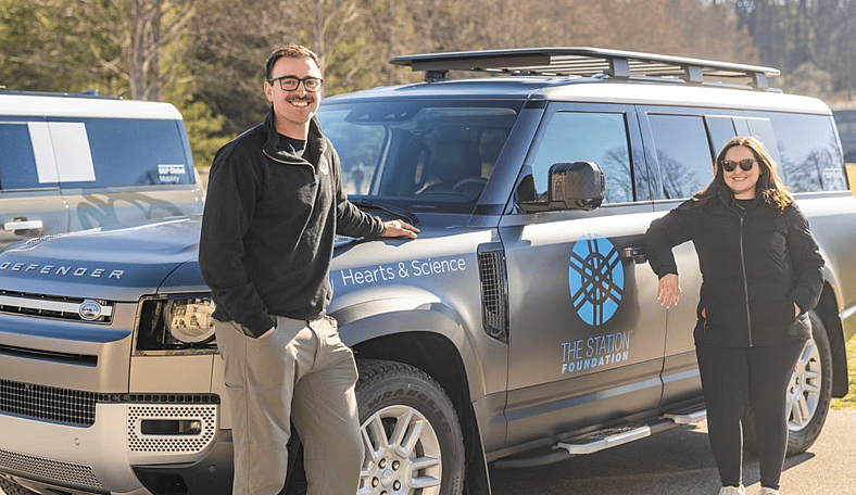 Two People Standing Next To A Custom Land Rover Defender 130 For The Defender Service Awards