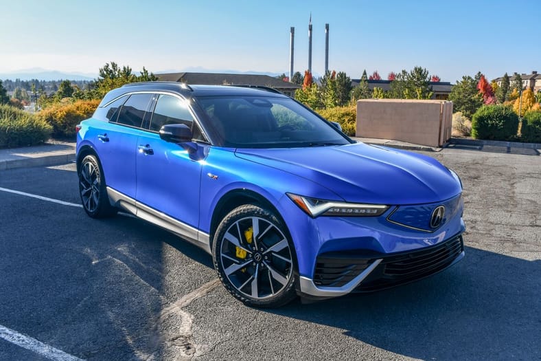 A 2024 Acura ZDX Type S EV posed with the Old Mill smokestacks in the background