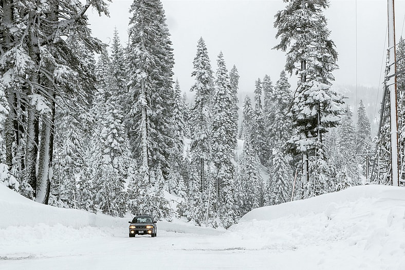 An Old Subaru Driving In The Snow Near Lake Tahoe