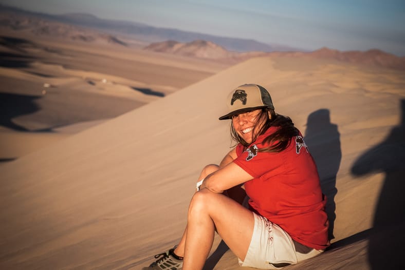 When "Total Chaos" Is Your Job: How Nicole Pitell-Vaughan Became the Go-To Builder for Off-Roaders 5 Nicole Sitting On A Sand Dune, Wearing Gear With Her Company'S Logo On It
