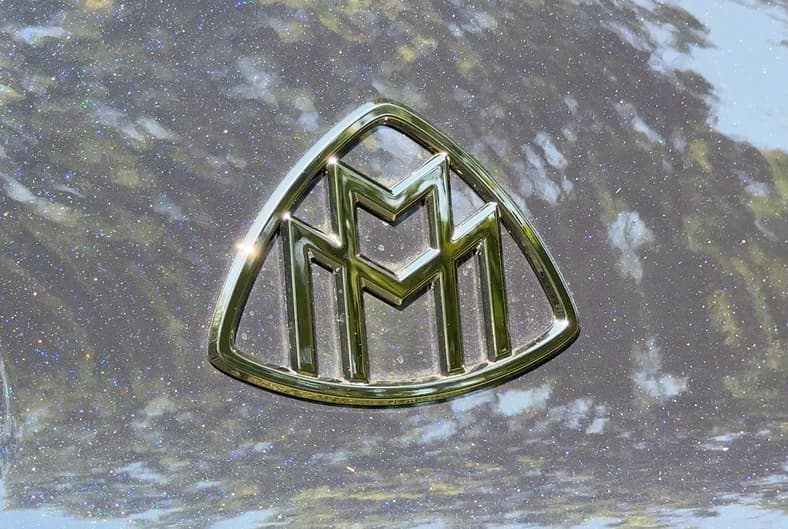 The 2027 Mercedes-Maybach S-Class Logo On The Rear Pillar Behind The Rear Doors, Sitting Amid A Metallic Glow In Our Test Model