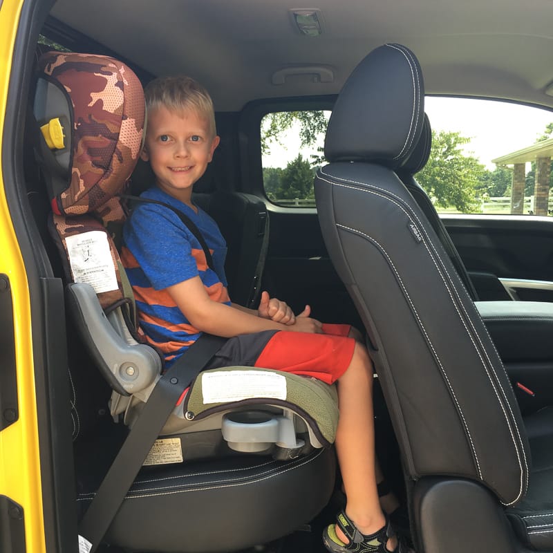 Kid in booster, front seat all the way back.