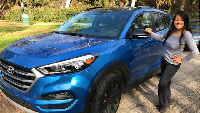 Woman standing next to a blue 2017 Hyundai Tucson compact crossover 