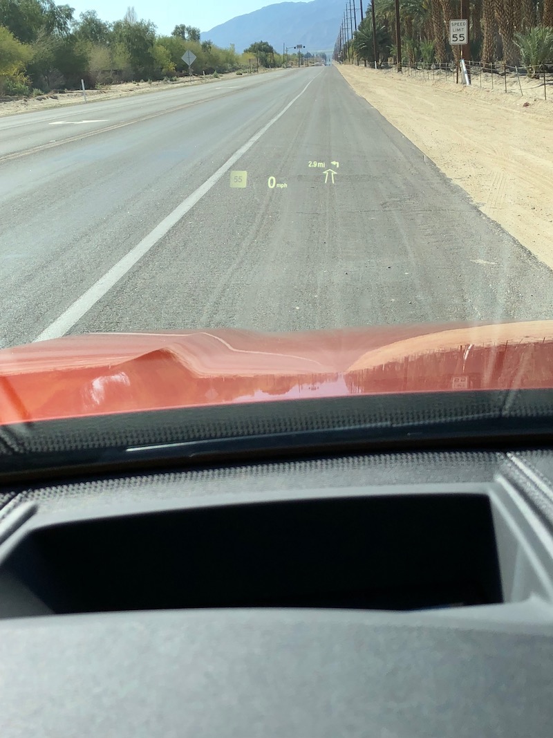 Head up display in the front X2 window against a road and mountain backdrop.
