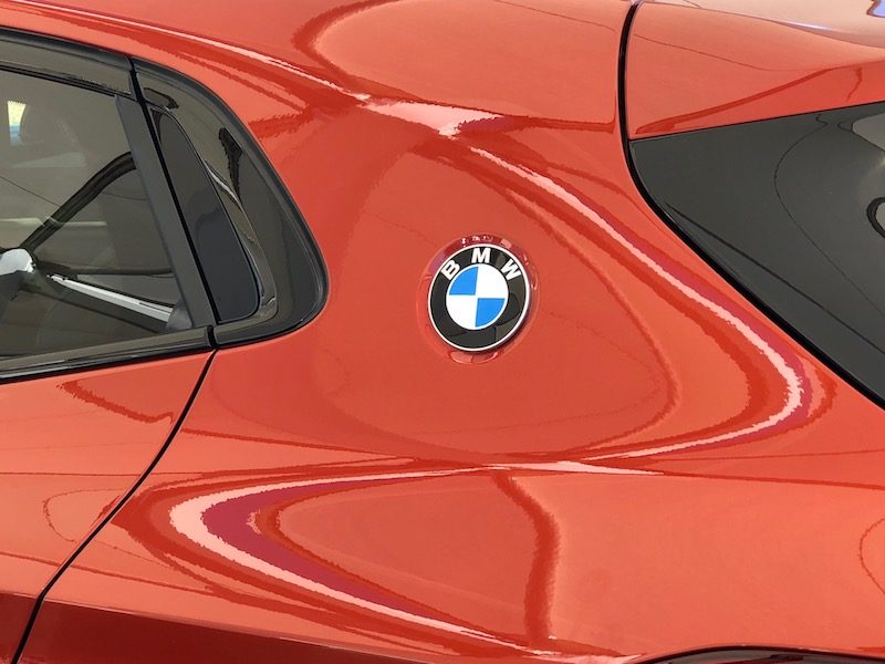 The BMW X2, in Sunset Orange Metallic sports a badge on the back panel near the rear hatch.
