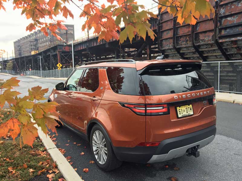 Orange Land Rover Discovery vehicle surrounded by fall leaves.