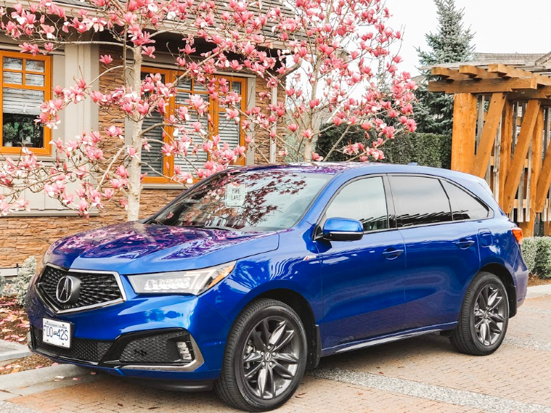 Blue Acura MDX in front of cherry blossoms