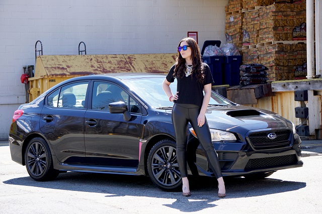 Woman posing in front of her black sports car 