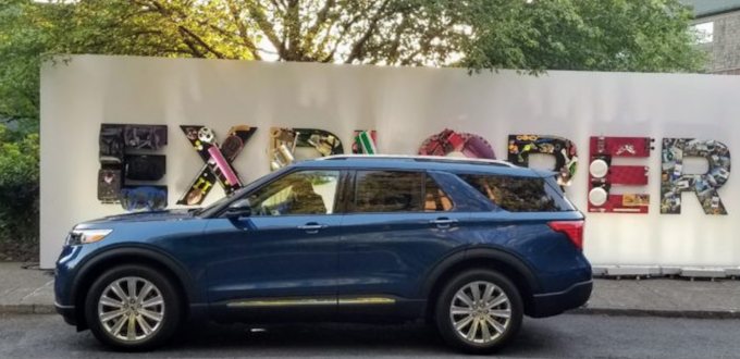 blue ford explorer parked in front of a decorative sign