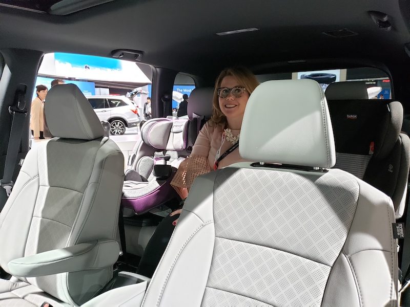 woman sitting in Honda's backseat in-between two car seats