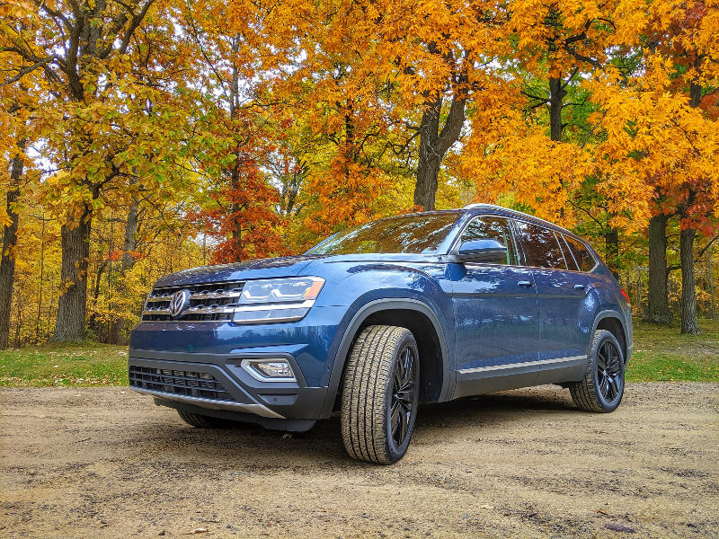 Blue Volkswagen Atlas among fall colored trees 