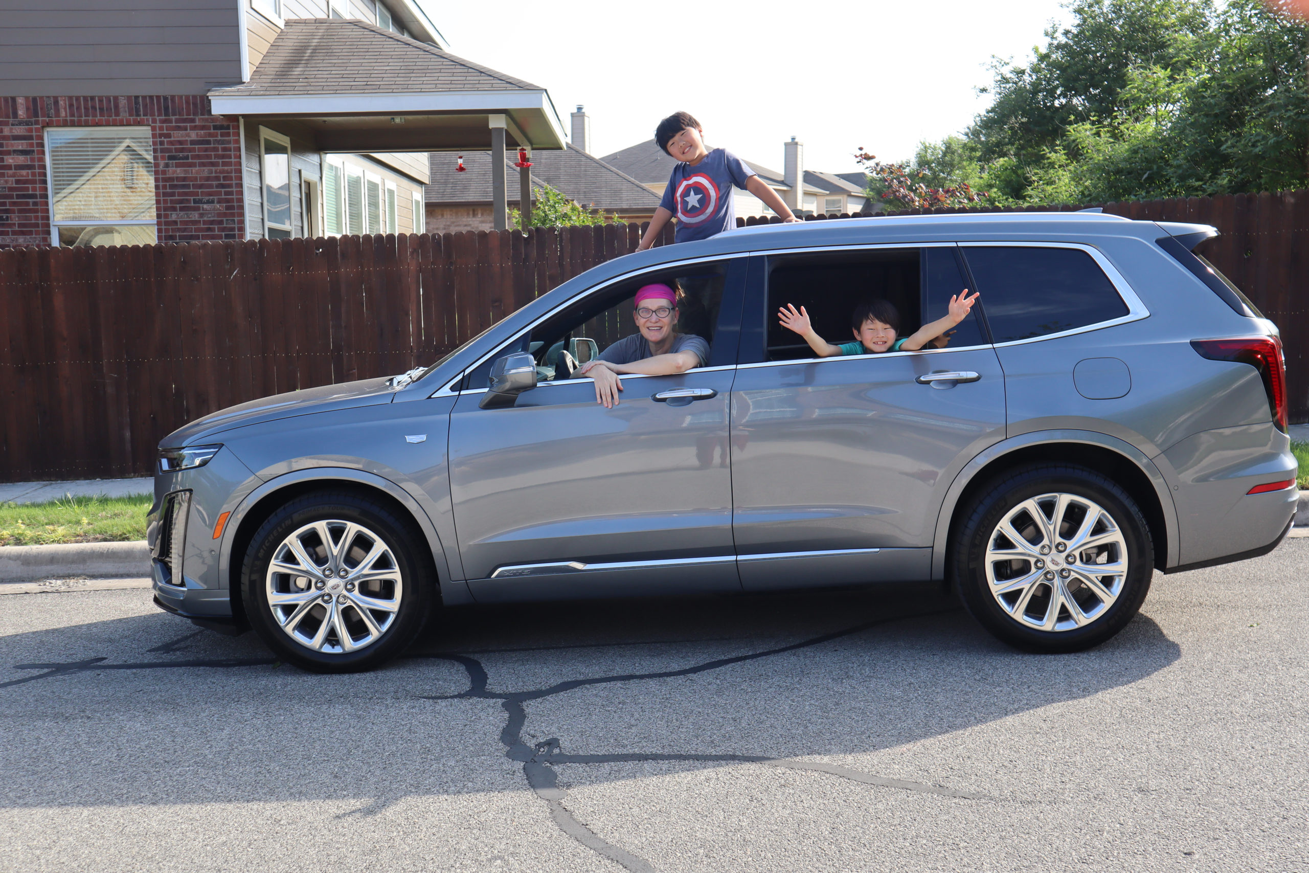 Cadillac XT6 with kiddos hanging out the sun room and back seat window