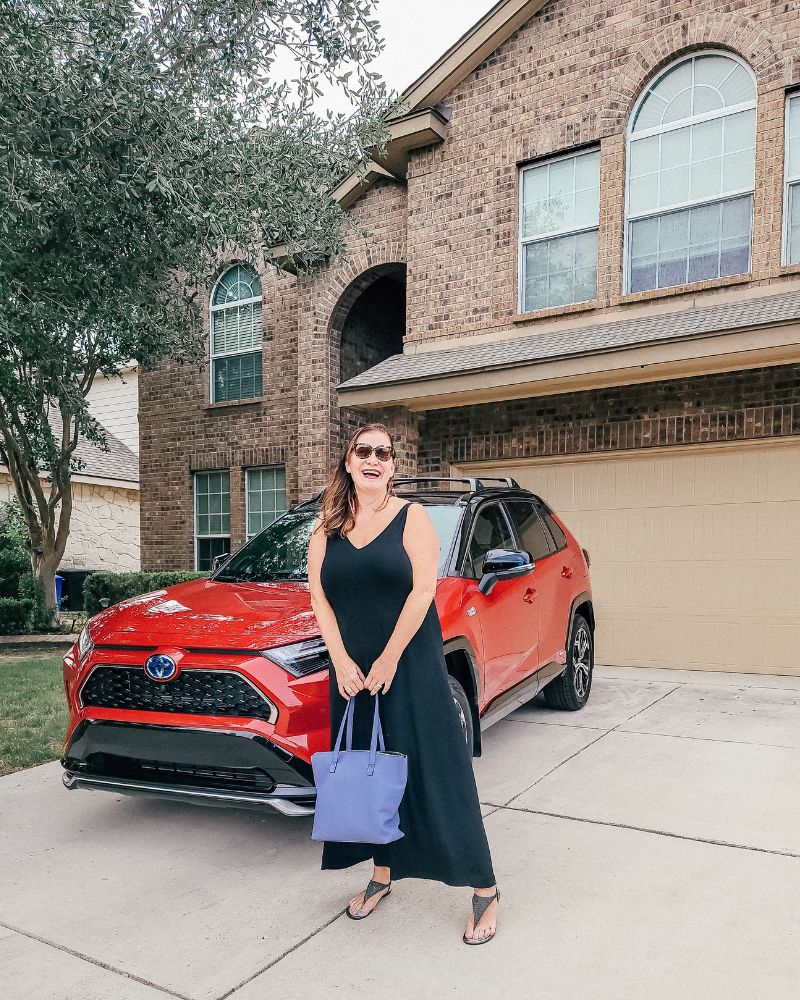 Woman in black dress in front of red toyota RAV4 plug in hybrid
