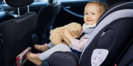 baby in car seat holding a teddy bear