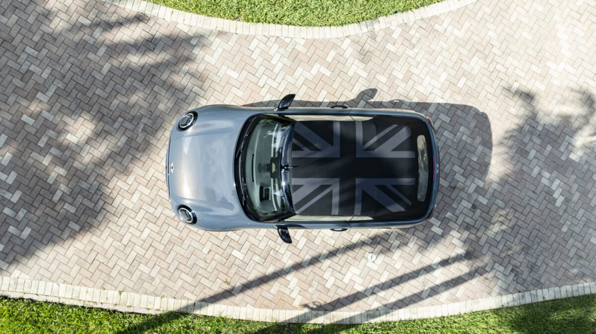 A 2025 Mini Cooper With The Optional Convertible Top Folded, Displaying The Union Jack Flag, Sitting In A Driveway