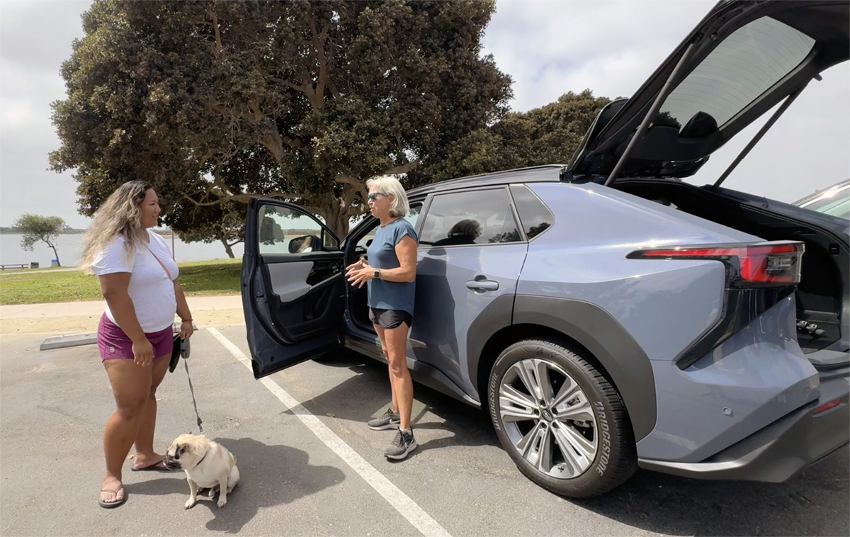 A Woman And Her Dog Admiring The Subaru Solterra