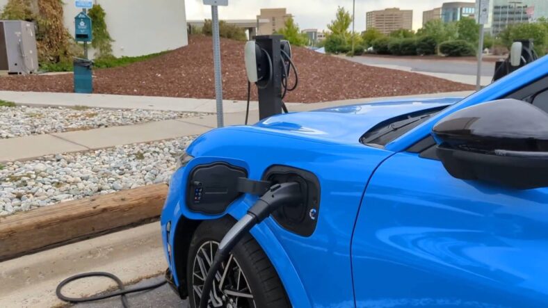 The Side Of The 2025 Mustang Mach-E At A Public Charger