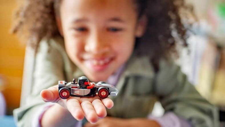 A Young Child Holding Up The A F1 Collectible From Lego